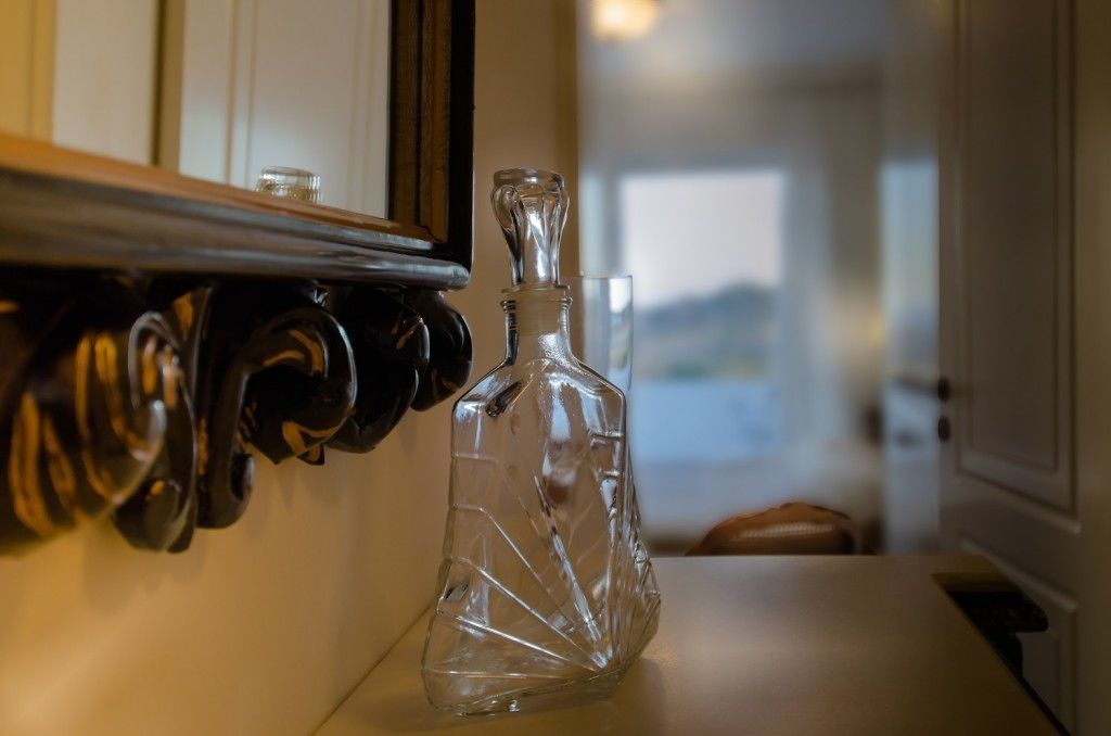 Une carafe en verre transparent est posée sur une table, à côté d’un meuble en bois doté d’un miroir.