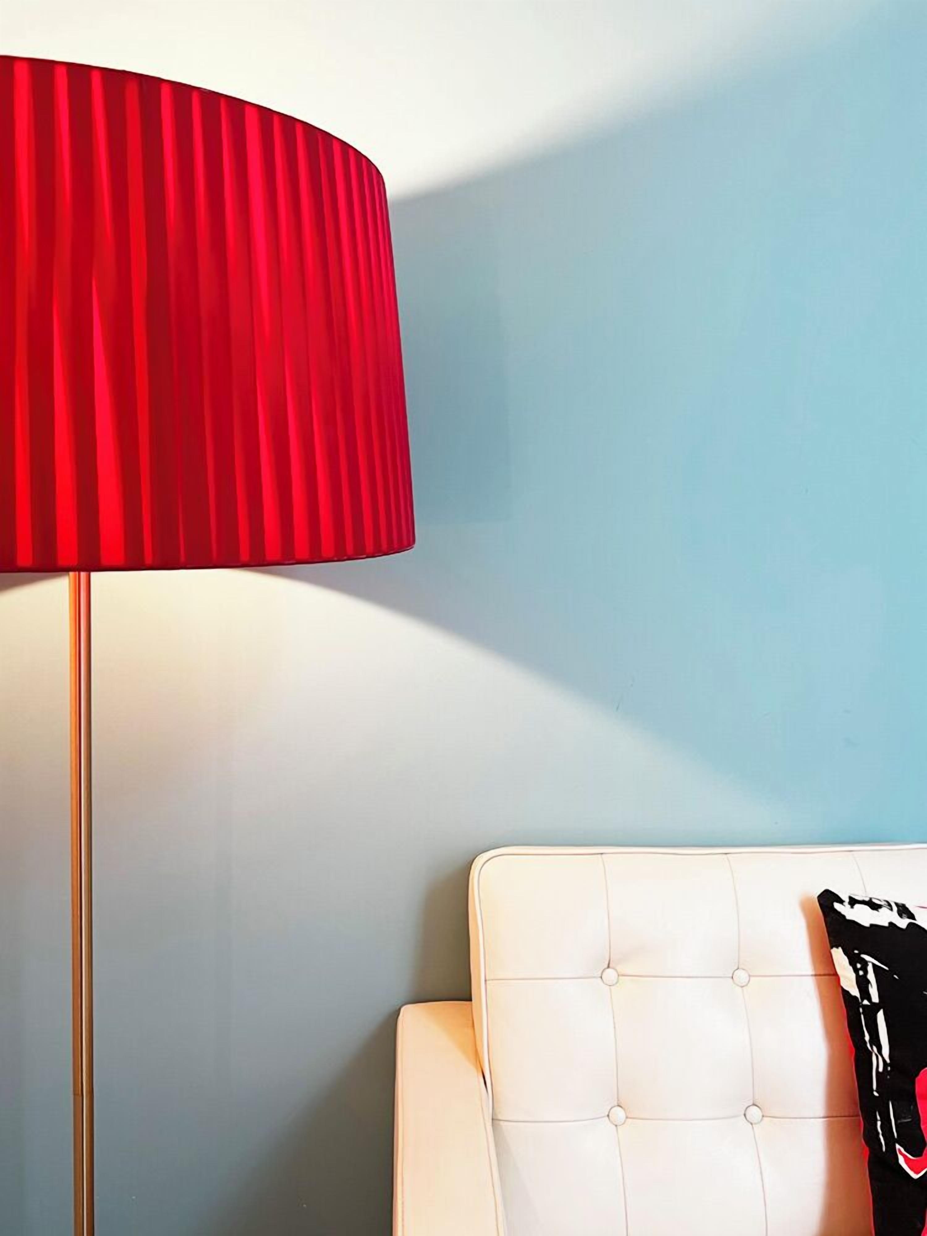 Ett rum med en röd lampa, en vit, vadderad stol och en vägg i ljusblå färg.