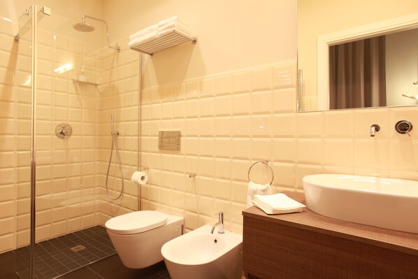 Un baño moderno con ducha de vidrio, lavamanos blanco y retrete.