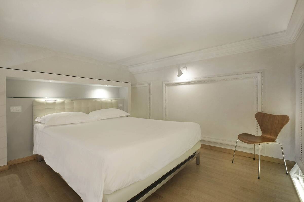 A bedroom with a bed, a chair, and a light fixture.