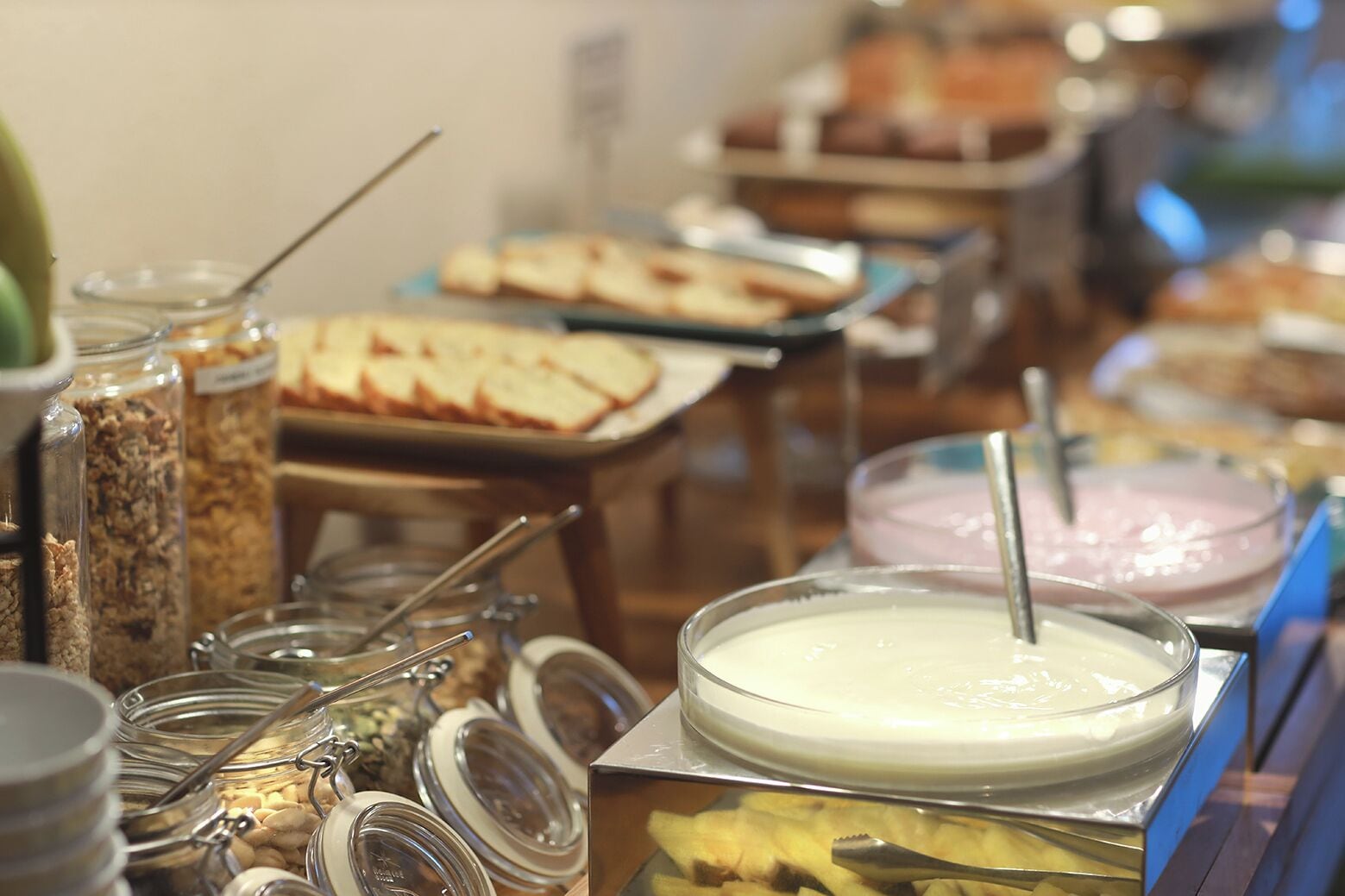 Un bufé con diversos alimentos, incluyendo un tazón de sopa, frascos de granola y una bandeja de pan.