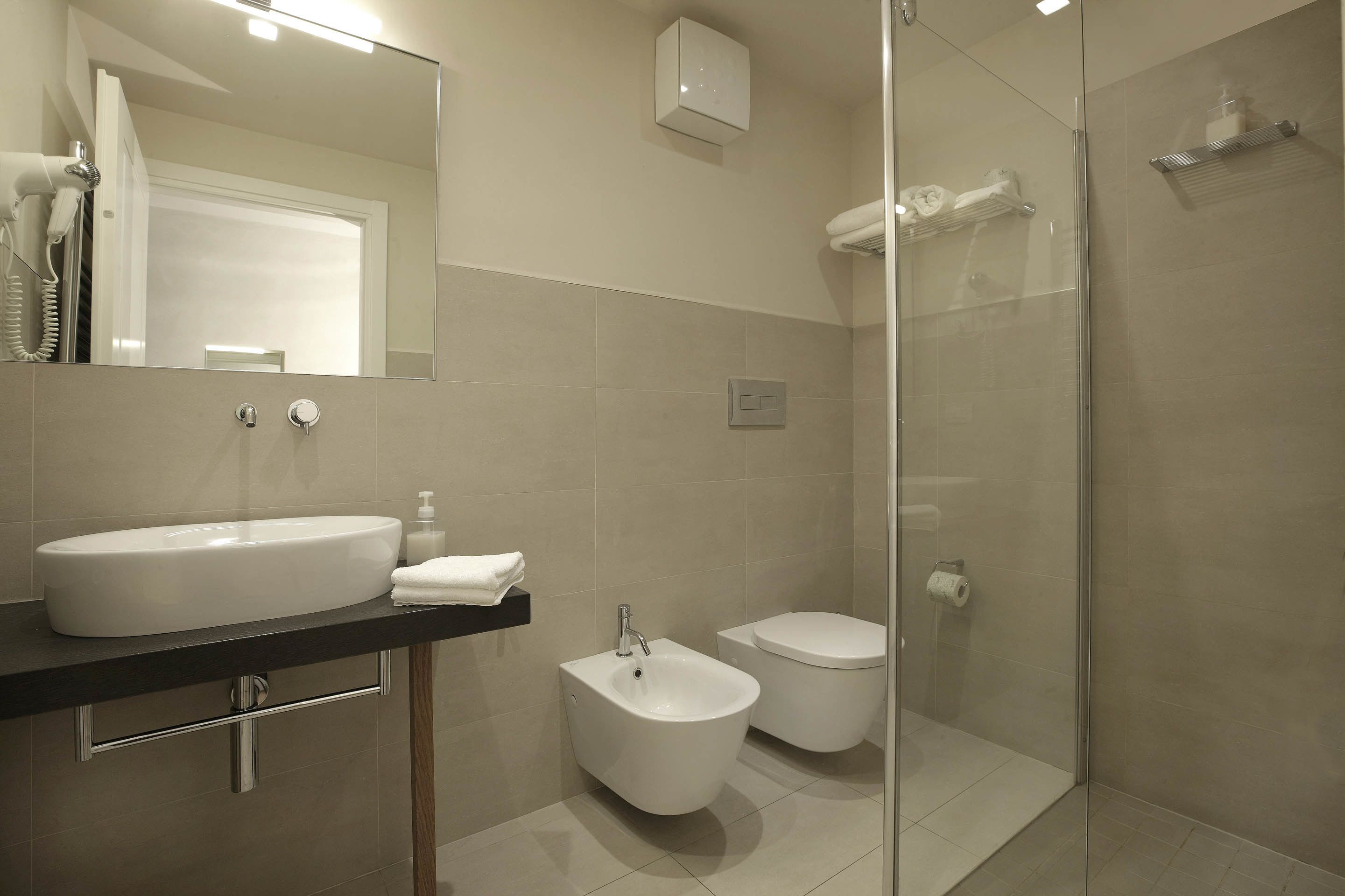 A modern bathroom with a large sink, bidet, toilet, and glass-enclosed shower.