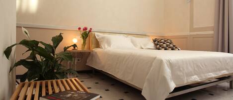 A neatly arranged bedroom with a bed, bedside table, and a potted plant.