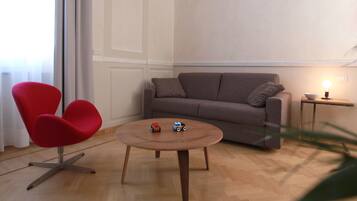 A living room with a brown sofa, a red chair, a small round table, and two toy cars.