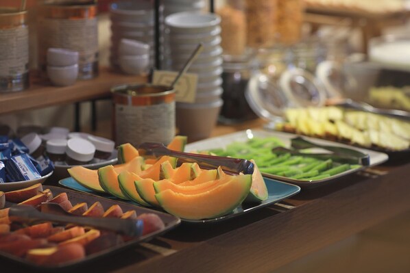 Un bufé con diversas frutas y verduras, incluyendo melón y judías verdes.