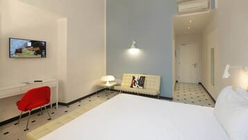 Een hotelkamer met een bed, een bureau, een stoel, een televisie, een bank en een lamp.