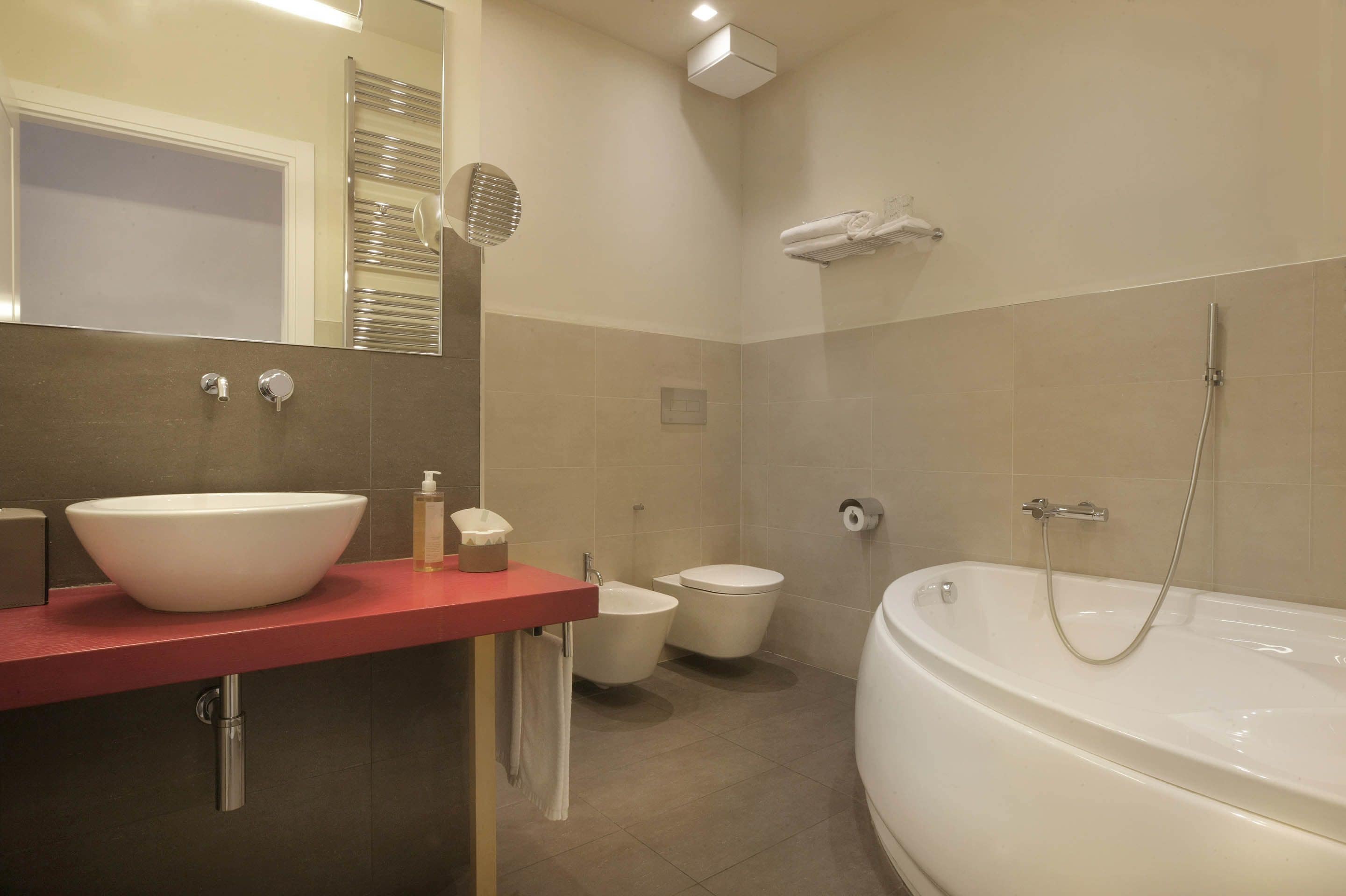 A modern bathroom with a large bathtub, a sink, a toilet, and a shower.