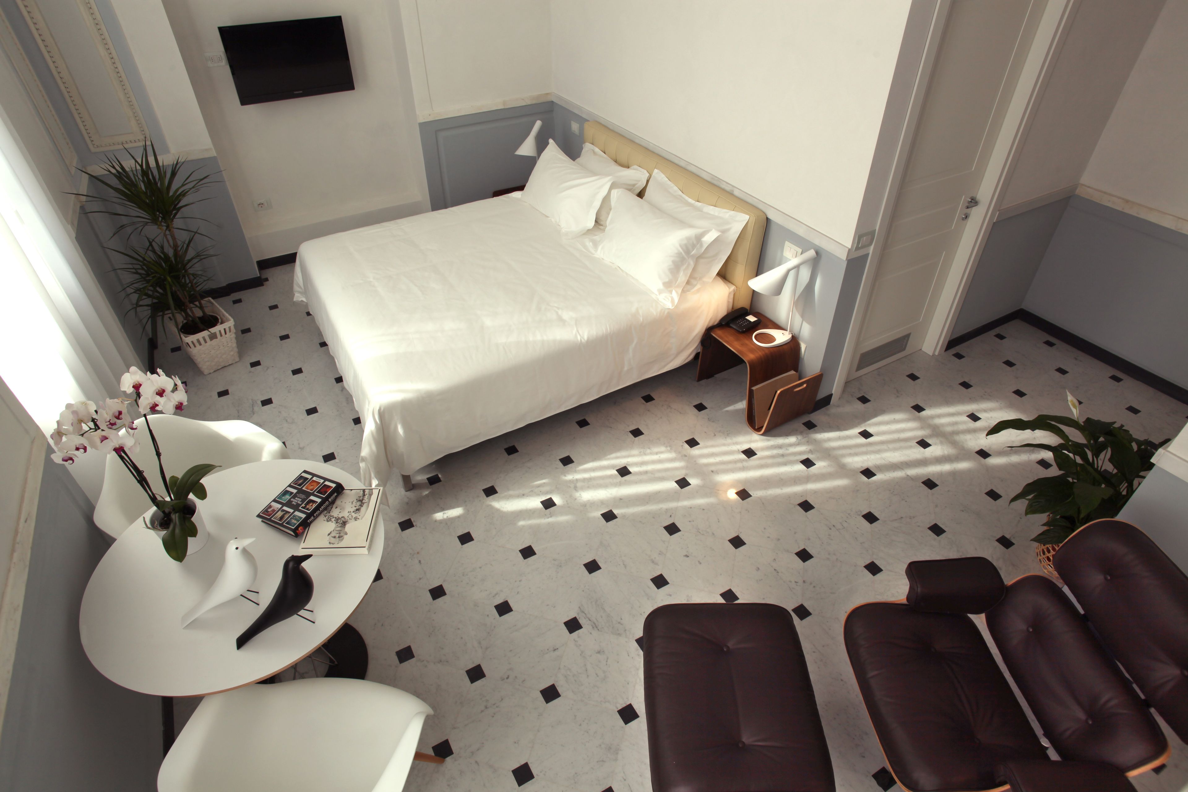 A hotel room with a bed, bedside table, lamp, and a seating area with chairs and a sofa.