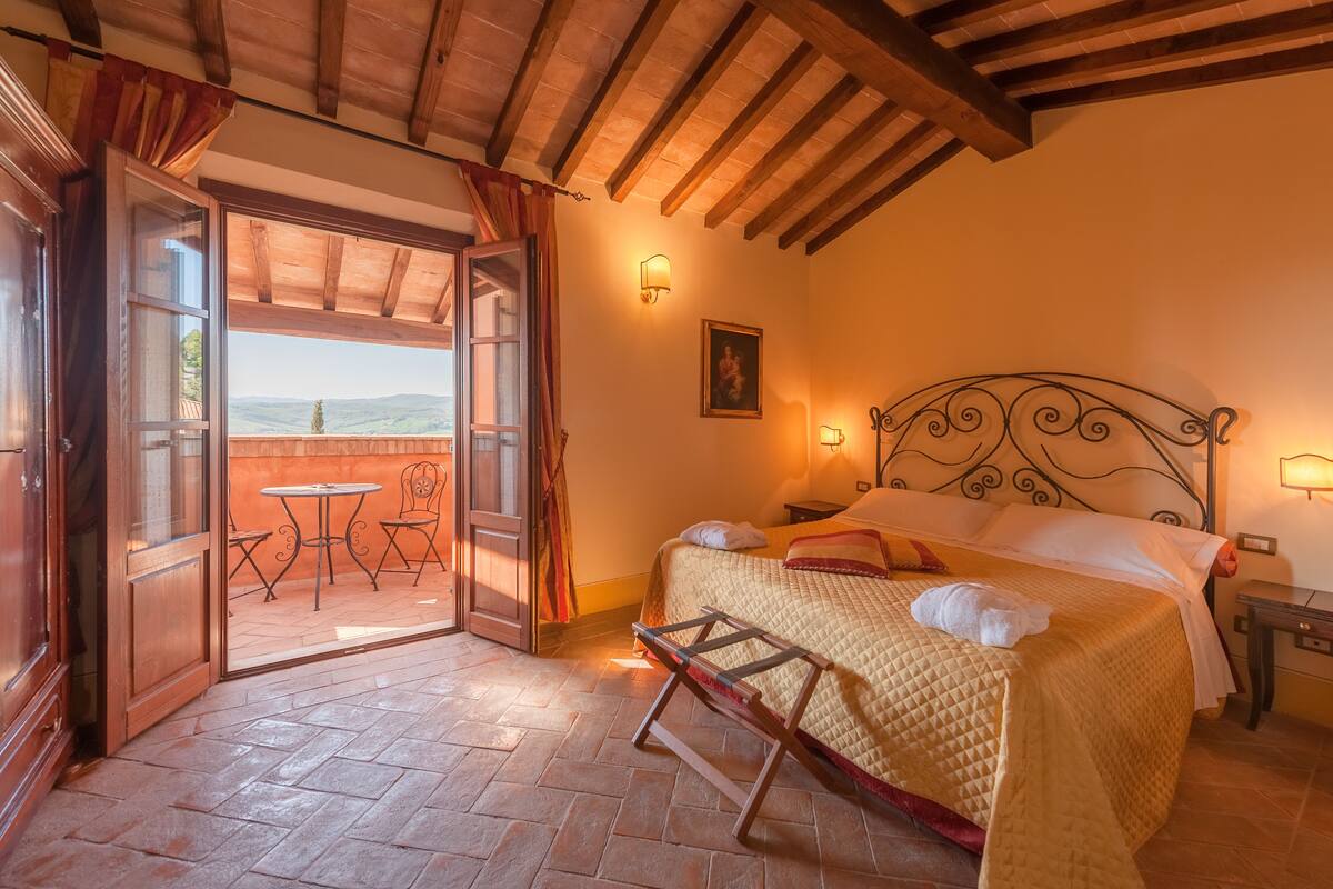 Un dormitorio con cama, ventana, puerta y vistas al exterior.