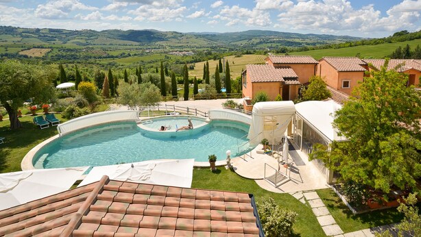 Une piscine entourée d’un jardin, avec en arrière-plan une vue sur des collines ondoyantes.