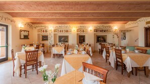 Un restaurant doté de nombreuses tables et chaises, d’un plafond en briques et d’étagères à vin fixées au mur.