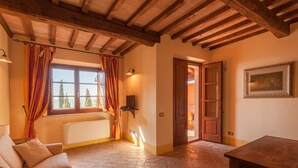 Une pièce avec un plafond en bois, un canapé, une table et une fenêtre avec des rideaux.