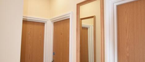 Un pasillo con puertas de madera, un espejo y una lámpara en el techo.