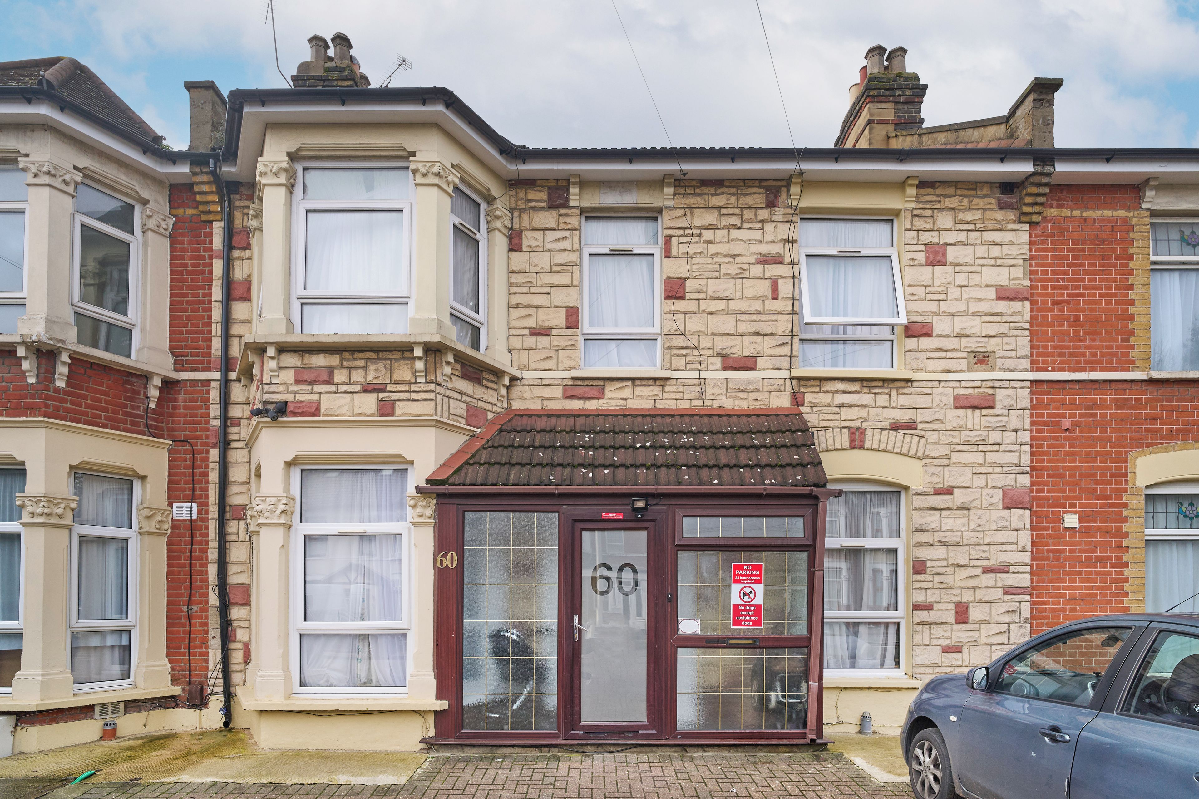 A row of terraced houses with a central building featuring a bay window and a door marked with the number 60.