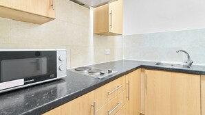 Una cocina con microondas, estufa, pileta y armarios de madera.