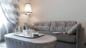 A modern living room with a grey sofa, patterned cushions, a lamp, and a small table with a tray.