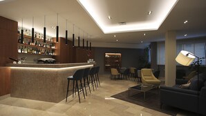 Zona de bar moderna con encimera de mármol, varios taburetes y una variedad de botellas de licores. Hay una sala de estar con un sofá, sillas y una mesa de centro. La habitación tiene un techo alto con iluminación empotrada y un tragaluz.