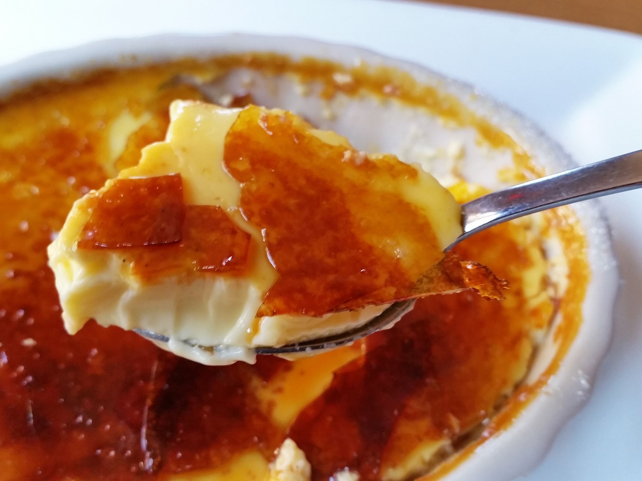 A spoonful of crème brûlée with caramelized sugar on top.