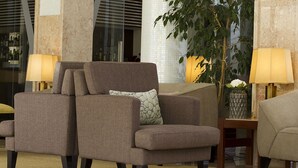 Un área de estar con dos sillones y un sofá, un jarrón con flores y dos lámparas.