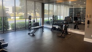 A gym with exercise equipment, large windows, and a view of the outside. - City Express by Marriott New Orleans 1-10 (New Orleans)