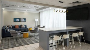 A modern hotel room with a sofa, chairs, a bar area, and a flat-screen TV. - City Express by Marriott New Orleans 1-10 (New Orleans)
