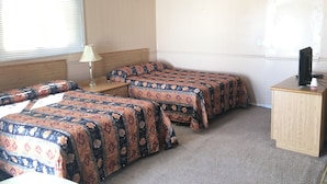 A room with two beds, a desk, and a television. - Bluebird Motel (Innisfail)