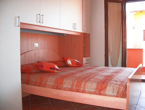A bedroom with a bed, two pillows, a nightstand, and a wardrobe. - Residence Ibiscus (Castelsardo)
