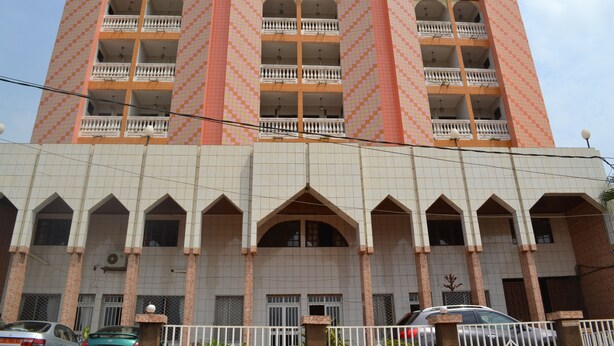 A multi-story hotel with a checkered facade, balconies, and a tiled ground floor. - Felydac Hotel (Yaoundé)