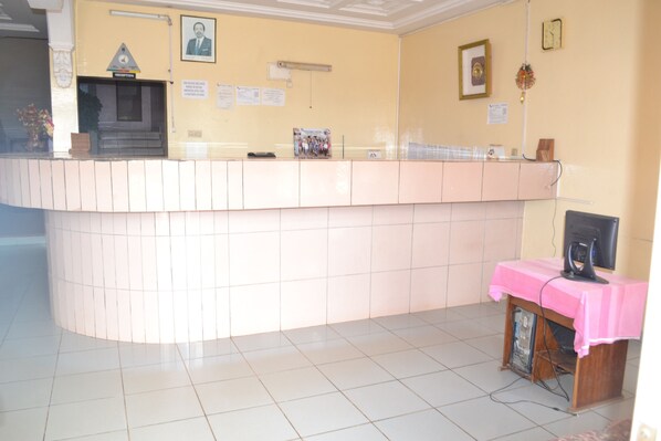 A reception area with a counter, a reception desk, a framed portrait, and a small table with a pink cloth.