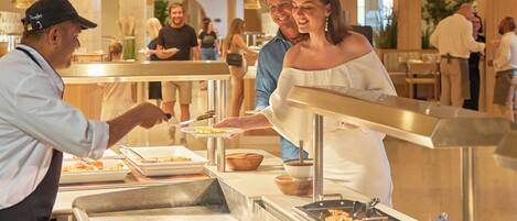 A buffet setup with various food items and a serving counter.
