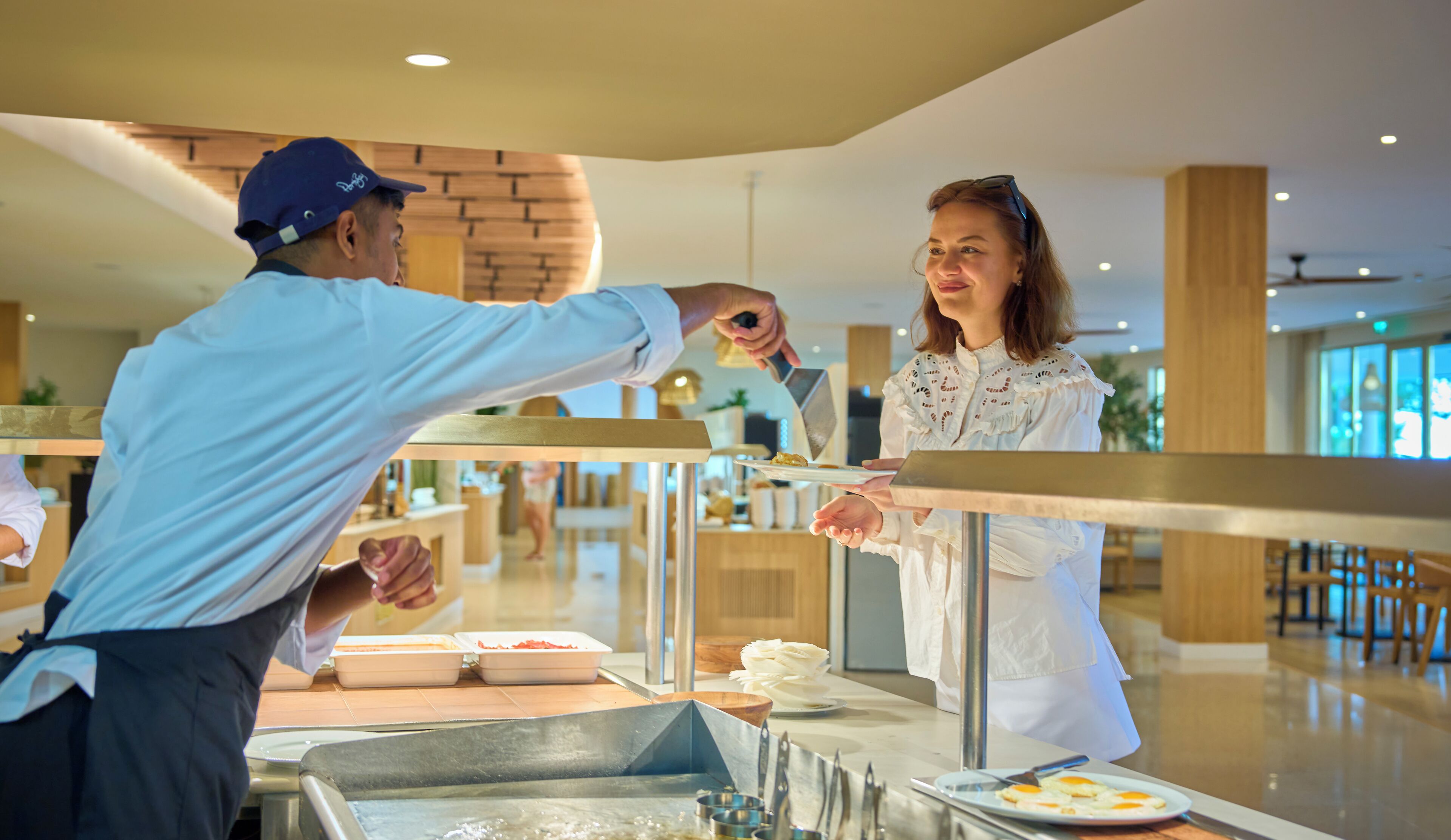 A buffet setup with a server and a guest.
