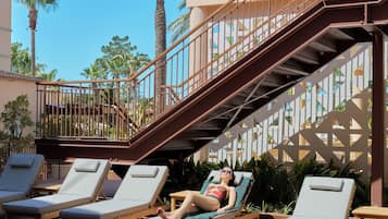 Zona de piscina con sillas de descanso y una escalera que lleva a un nivel superior.