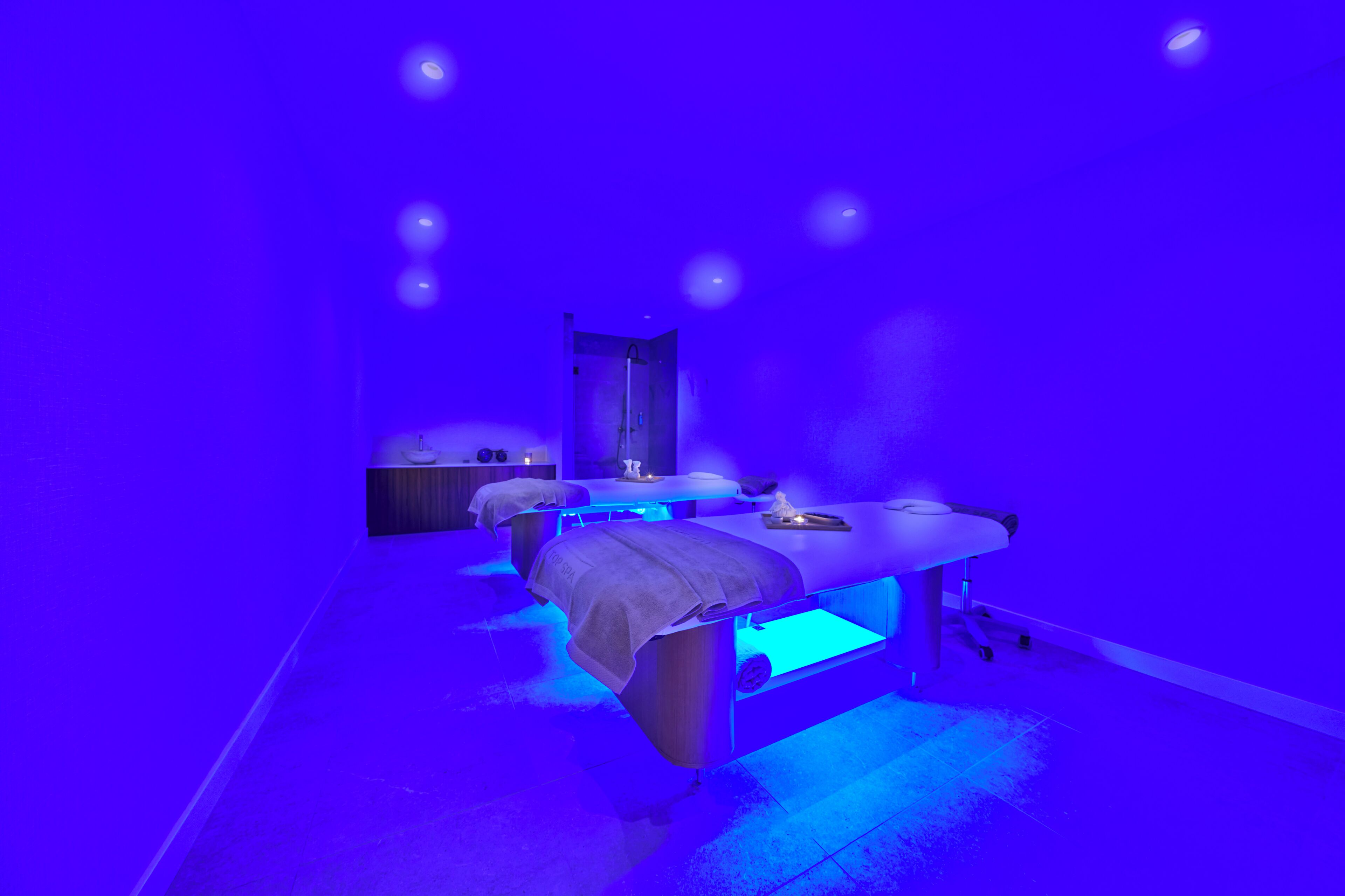 A room with three massage tables, each with a towel and a small table.