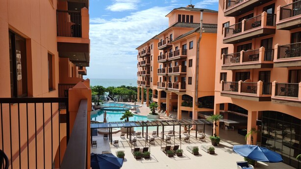Un hotel con piscina, mobiliario exterior y balcones con vistas al agua.