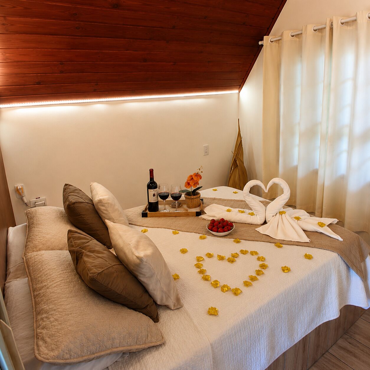 Een gezellige kamer met een bed, kussens, een dienblad met een fles, glazen en bloemen.