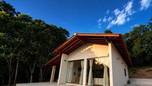 Una casa moderna con techo inclinado, grandes puertas de cristal y un porche de hormigón.