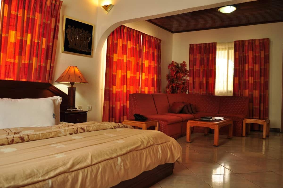 Ein Hotelzimmer mit Bett, einer Couch, einem Couchtisch und Vorhängen.