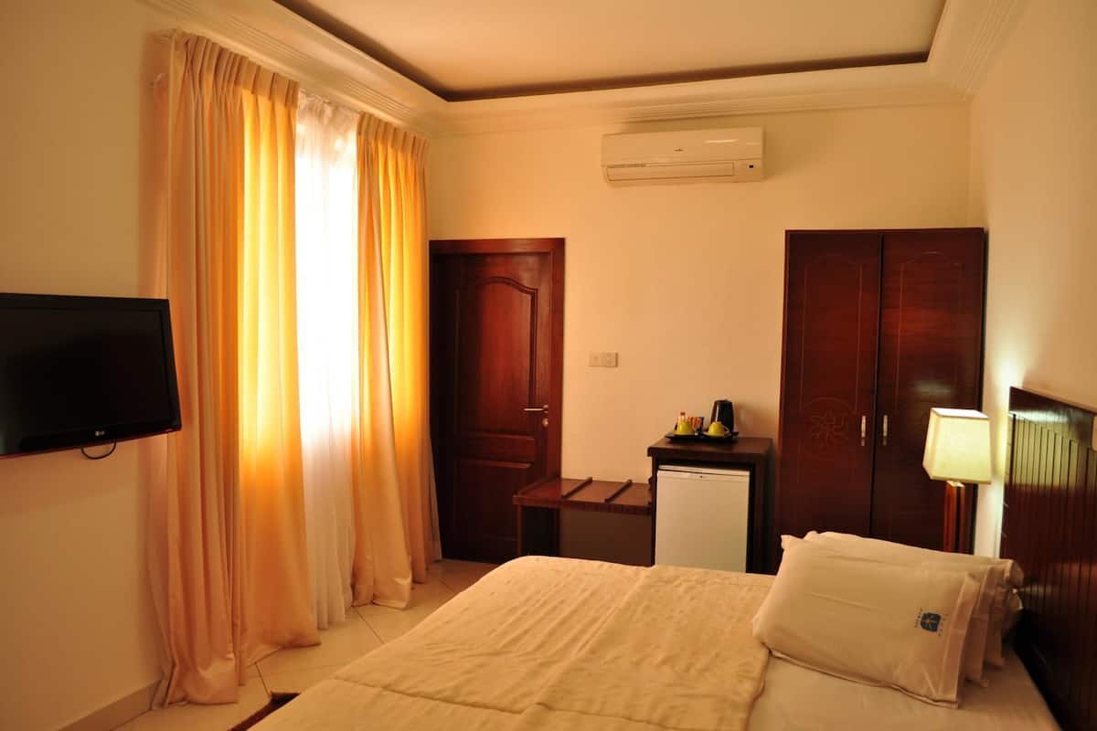 Ein Hotelzimmer mit Bett, Fernseher, Schreibtisch mit Lampe und Kleiderschrank.
