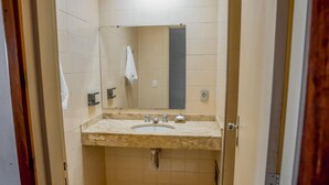 Ein kleines Badezimmer mit Waschbecken, Spiegel und Handtuch an der Wand.
