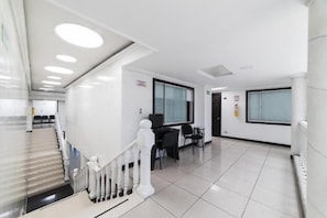 A modern hotel lobby with a staircase, a reception desk, and a seating area.