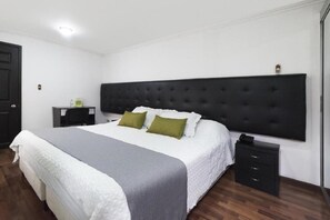 A neatly arranged bedroom with a large bed, a bedside table, and a nightstand.
