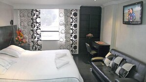 Una habitación de hotel con cama, sofá, escritorio y televisión.