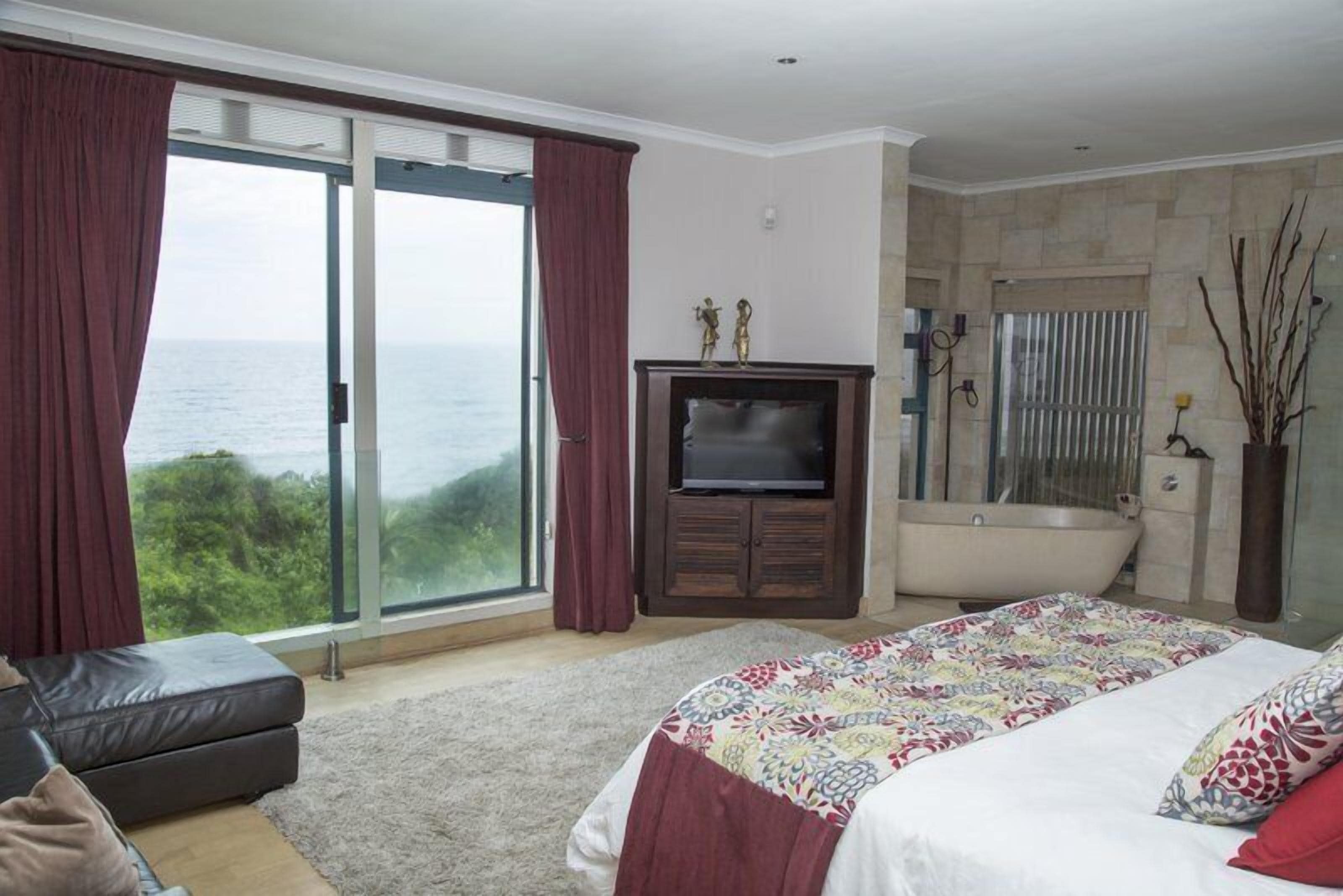 Ein Schlafzimmer mit einem großen Bett, einem Fernseher, einer Badewanne und Meerblick.