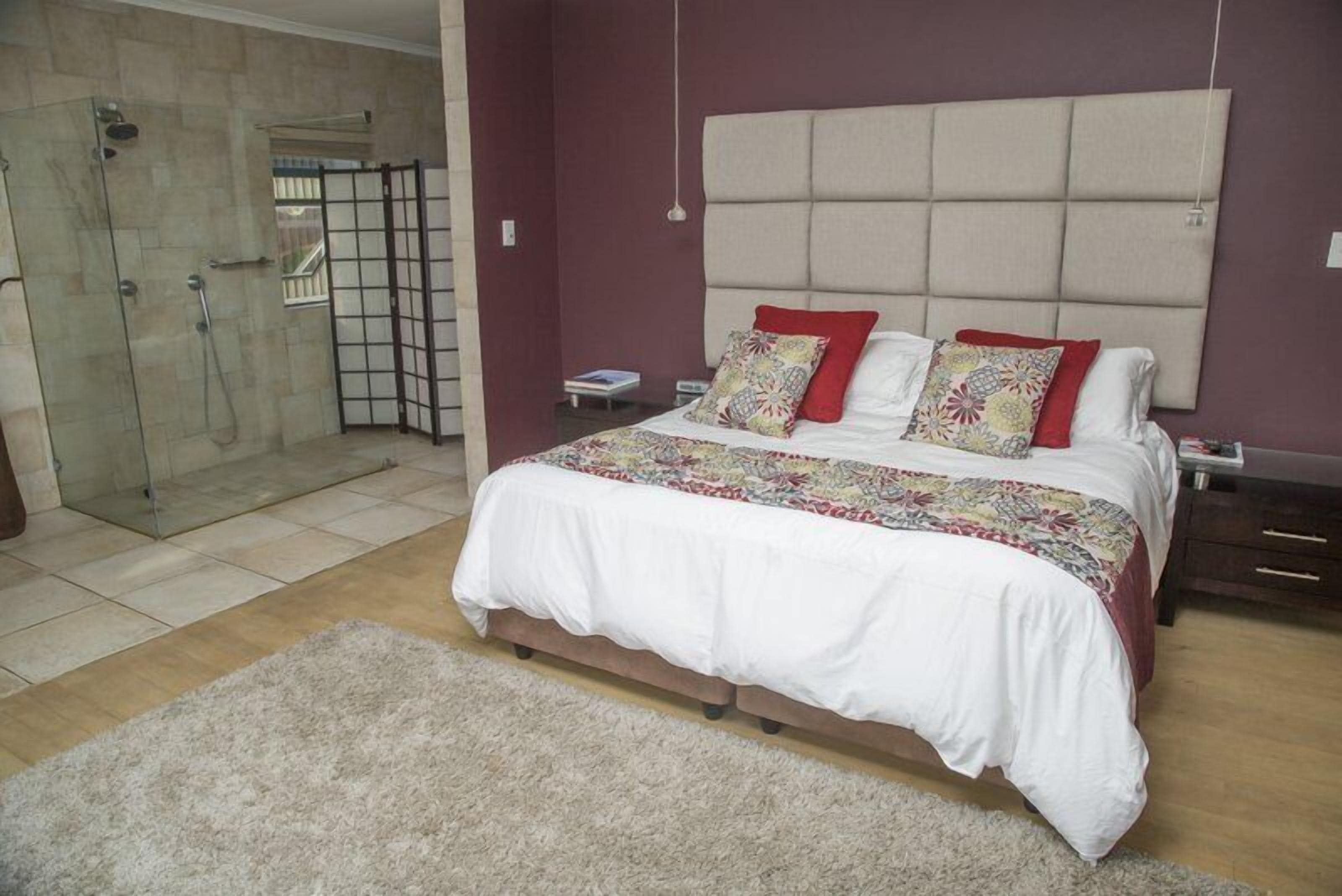 Une chambre dotée d’un grand lit, d’une table de chevet, d’une commode, d’une cabine de douche en verre et offrant une vue sur l’extérieur.