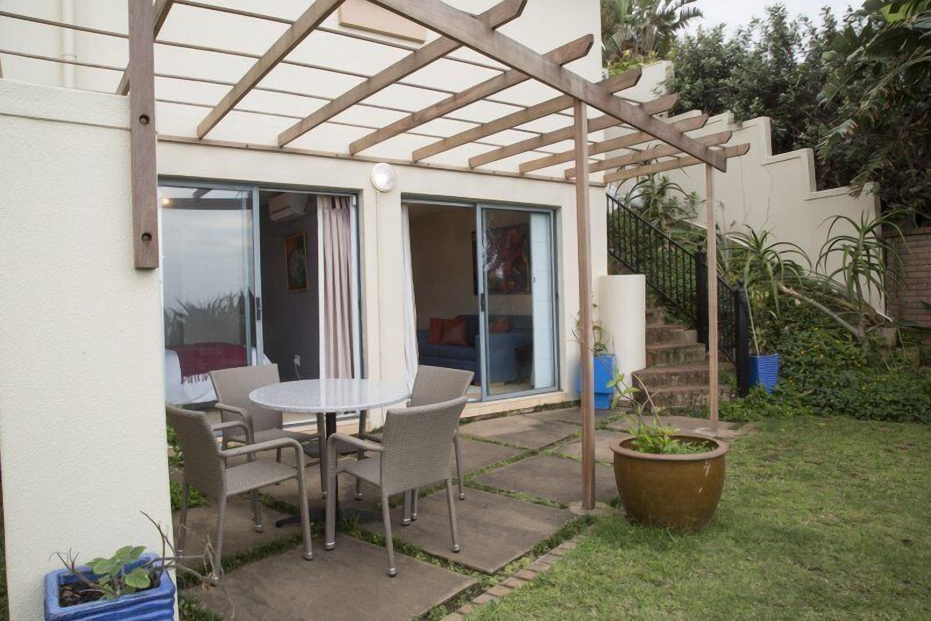 A patio with a table and chairs, a pergola, and a potted plant.