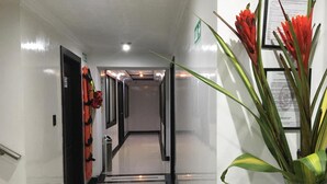 A hotel hallway with a shiny tiled floor, doors on both sides, and a potted plant on the right. - Hotel Ejecutivo Embajada (Bogotá)