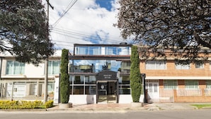 A modern building with a glass facade, a sign reading "Calle 24 B 44 22", and a gated entrance. - Hotel Ejecutivo Embajada (Bogotá)