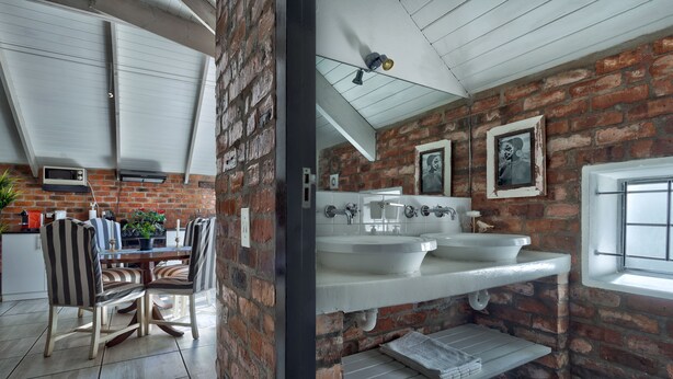 A kitchen with a dining table and chairs, a brick wall, and a window.
