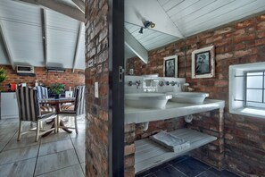 Una cocina con una mesa de comedor y sillas, un muro de ladrillo y una ventana.