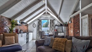 A cozy living room with a brown leather sofa, a dining area, and a kitchen.